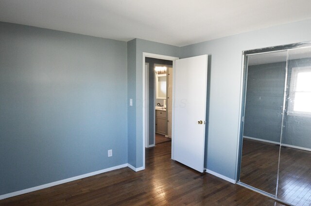 unfurnished bedroom featuring a closet and dark hardwood / wood-style flooring