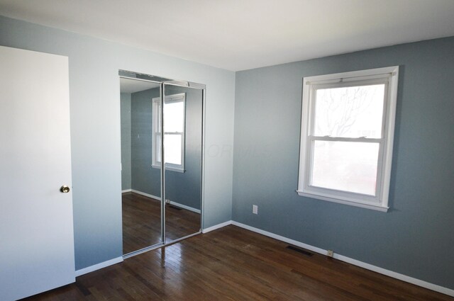 unfurnished bedroom with dark hardwood / wood-style flooring and a closet