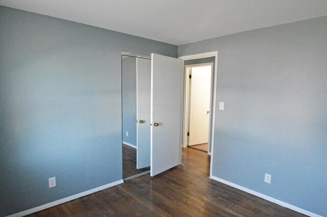 unfurnished bedroom featuring dark hardwood / wood-style flooring and a closet