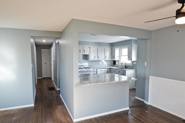 kitchen with white cabinets, dark hardwood / wood-style flooring, light stone counters, and white gas stove