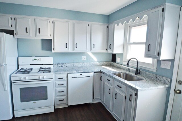 kitchen with light stone countertops, white appliances, dark wood-type flooring, sink, and white cabinetry