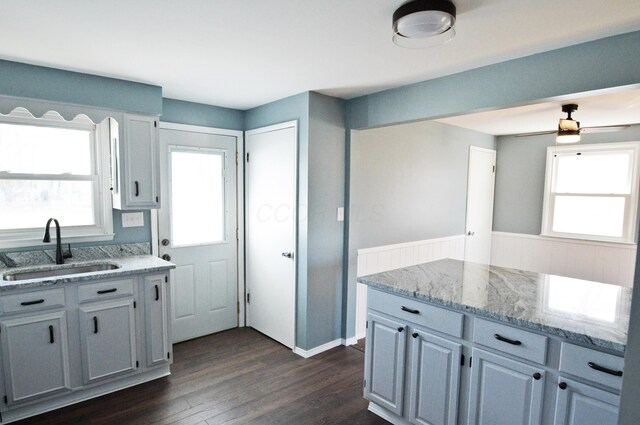 kitchen with dark hardwood / wood-style flooring, a wealth of natural light, sink, and light stone countertops