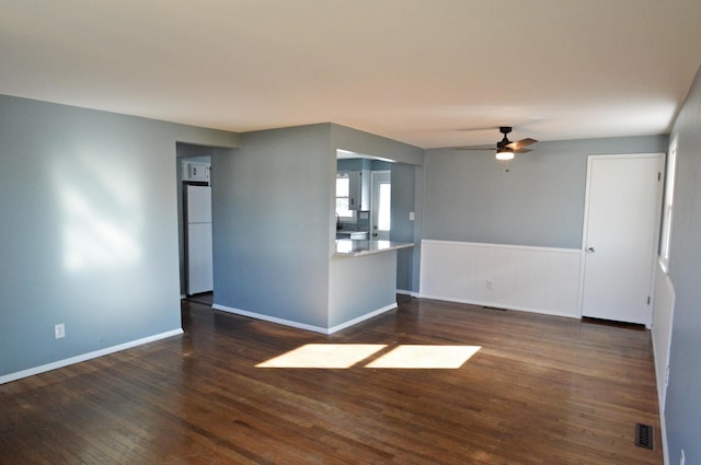 unfurnished living room featuring ceiling fan and dark hardwood / wood-style floors