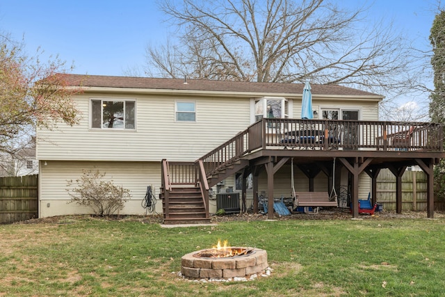 back of property featuring a fire pit, a deck, a lawn, and central air condition unit