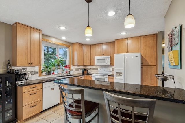 kitchen with a breakfast bar, sink, white appliances, and hanging light fixtures