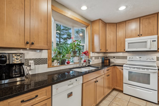 kitchen featuring a textured ceiling, white appliances, dark stone counters, and sink