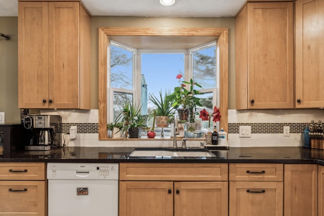 kitchen with dishwasher, dark stone countertops, sink, and backsplash