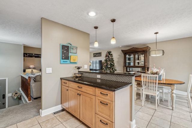 kitchen with kitchen peninsula, a textured ceiling, decorative light fixtures, and light tile patterned flooring