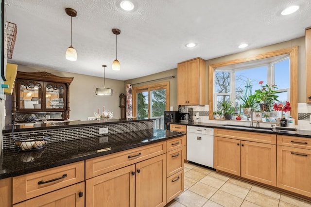 kitchen with dishwasher, backsplash, hanging light fixtures, dark stone countertops, and light tile patterned flooring