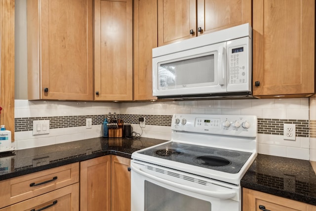 kitchen with white appliances, tasteful backsplash, and dark stone countertops