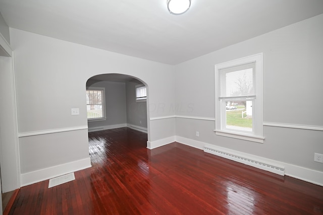 empty room with hardwood / wood-style flooring, a wealth of natural light, and a baseboard radiator