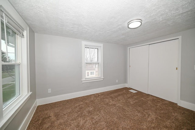 unfurnished bedroom featuring carpet floors, a textured ceiling, and a closet