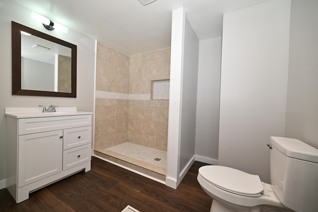 bathroom with a tile shower, toilet, vanity, and hardwood / wood-style flooring