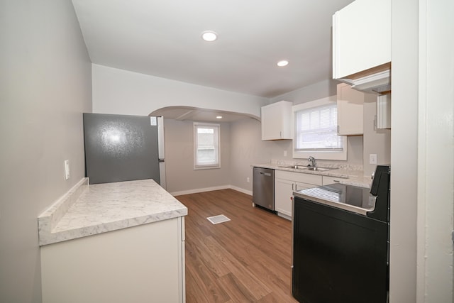 kitchen with hardwood / wood-style floors, plenty of natural light, white cabinets, and stainless steel appliances