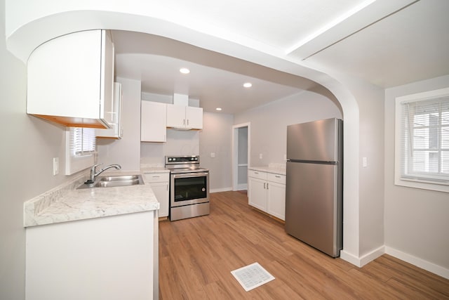 kitchen with white cabinetry, sink, appliances with stainless steel finishes, and light hardwood / wood-style flooring