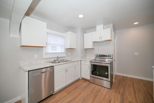 kitchen with light stone countertops, sink, appliances with stainless steel finishes, white cabinets, and light wood-type flooring