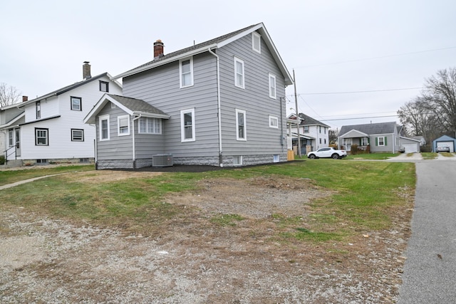 view of side of home featuring a yard and central AC