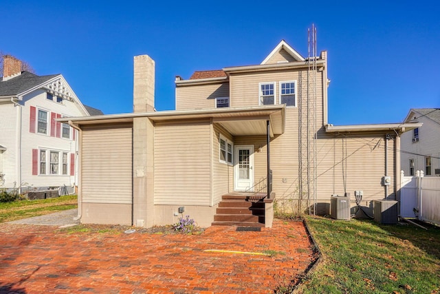 back of property with a yard and central AC unit