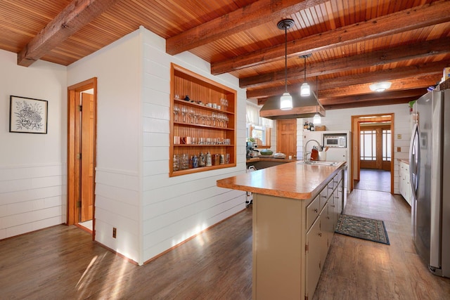 kitchen with stainless steel refrigerator, beamed ceiling, an island with sink, and wood ceiling