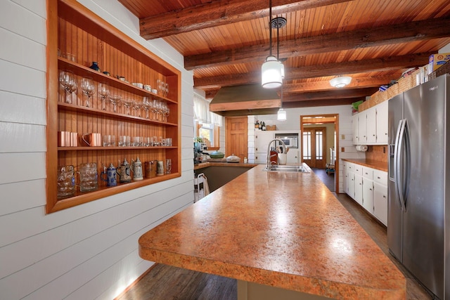 kitchen featuring stainless steel refrigerator with ice dispenser, wood ceiling, wooden walls, decorative light fixtures, and white cabinetry