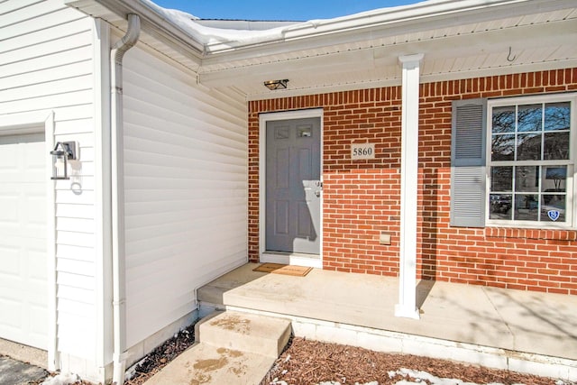 doorway to property featuring brick siding and an attached garage