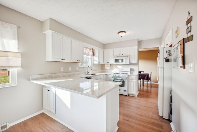 kitchen with kitchen peninsula, white appliances, and white cabinets