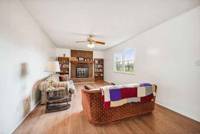 living room with ceiling fan, a fireplace, and hardwood / wood-style flooring