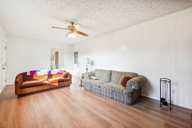 living room featuring hardwood / wood-style flooring, ceiling fan, and a textured ceiling