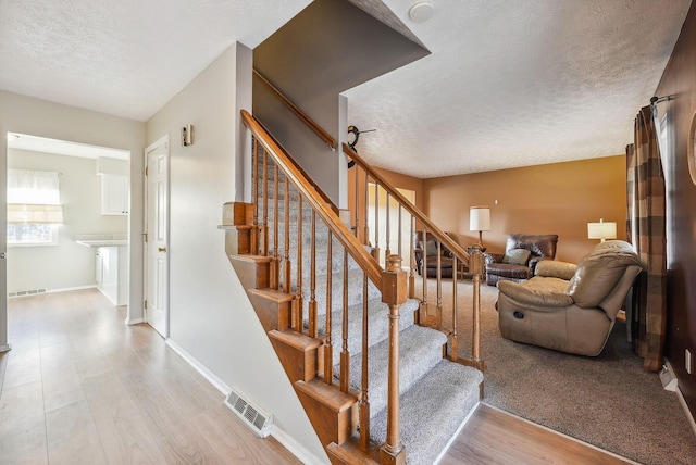 stairs with hardwood / wood-style flooring and a textured ceiling