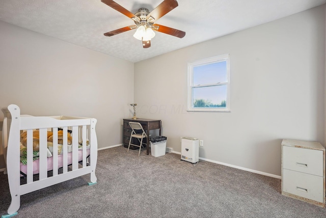 carpeted bedroom featuring ceiling fan, a textured ceiling, and a nursery area