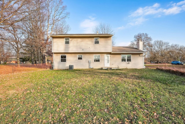 rear view of property with central AC and a lawn