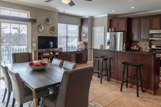 dining area featuring a healthy amount of sunlight, light tile patterned flooring, and crown molding