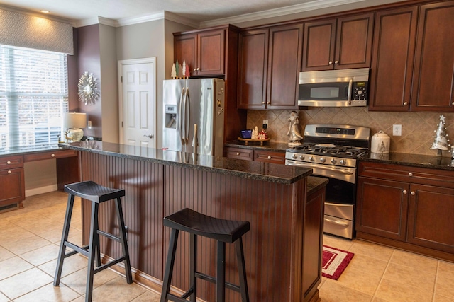 kitchen with a kitchen breakfast bar, dark stone countertops, appliances with stainless steel finishes, and tasteful backsplash