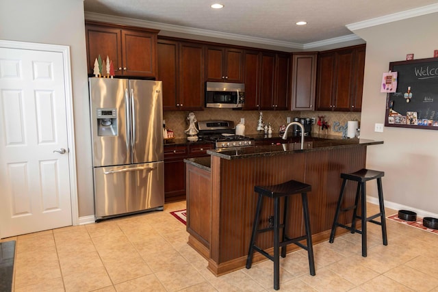 kitchen featuring ornamental molding, a breakfast bar area, appliances with stainless steel finishes, and tasteful backsplash