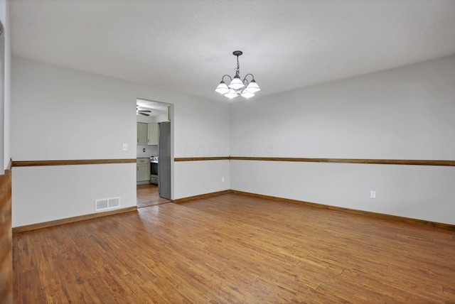 spare room featuring light hardwood / wood-style floors and a notable chandelier