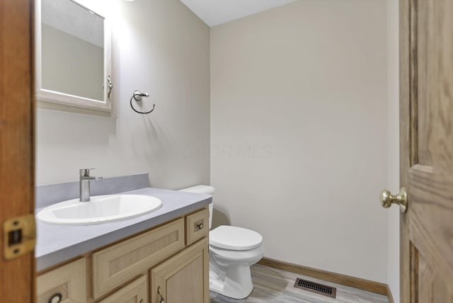 bathroom with wood-type flooring, vanity, and toilet