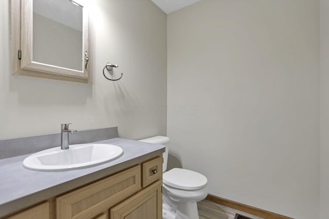 bathroom with hardwood / wood-style floors, vanity, and toilet