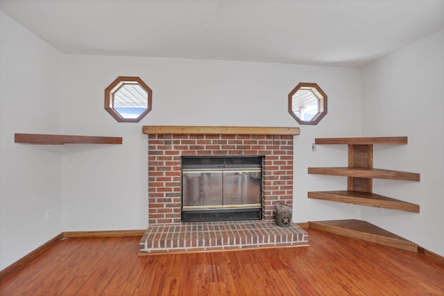 unfurnished living room with hardwood / wood-style flooring and a brick fireplace