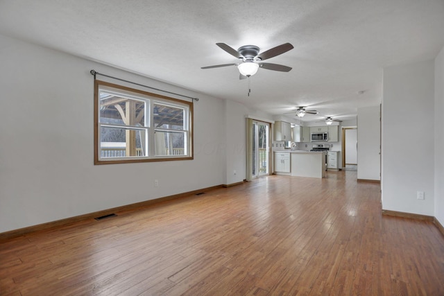 unfurnished living room featuring ceiling fan, light hardwood / wood-style flooring, and a textured ceiling