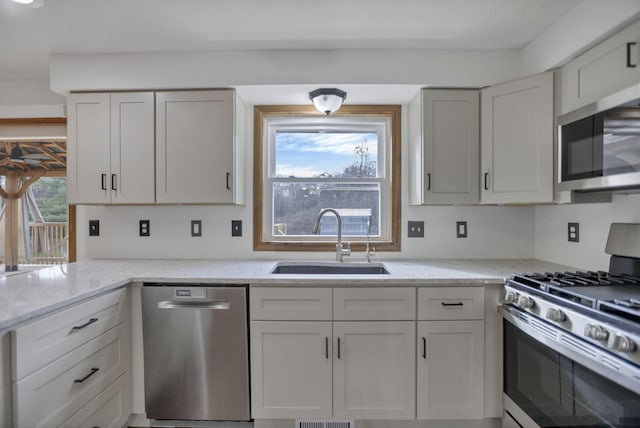 kitchen with appliances with stainless steel finishes, white cabinetry, plenty of natural light, and sink