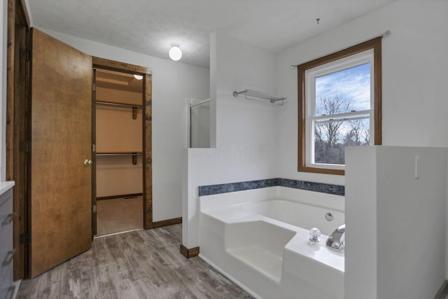 bathroom with hardwood / wood-style floors, plus walk in shower, and a textured ceiling