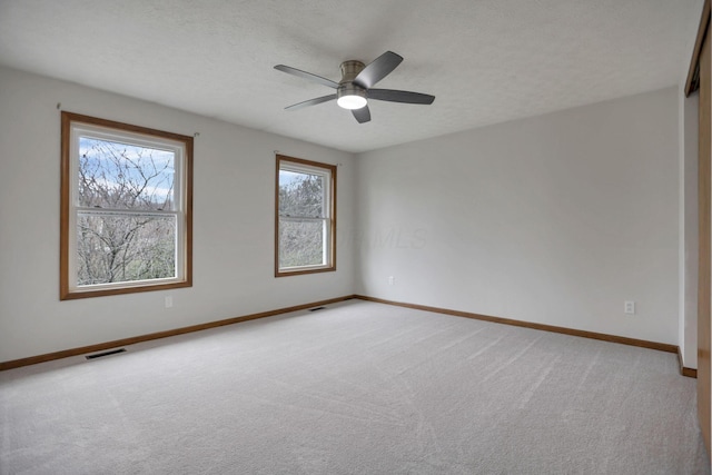 unfurnished room with a textured ceiling, ceiling fan, and light carpet