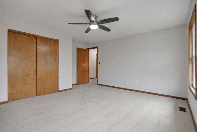 unfurnished bedroom featuring ceiling fan, light colored carpet, and a closet