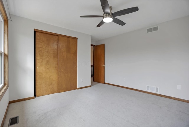 unfurnished bedroom with ceiling fan, a closet, and light carpet