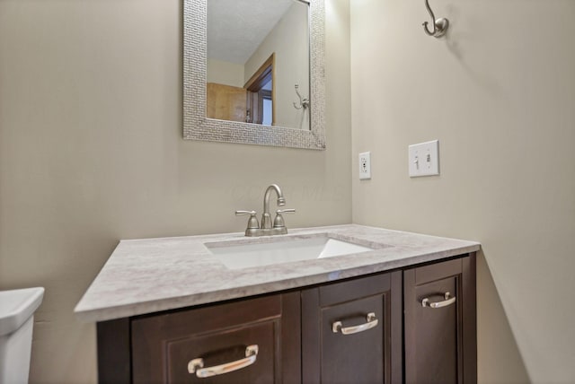 bathroom featuring vanity, a textured ceiling, and toilet