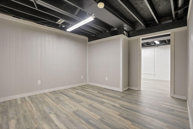 basement with wood walls and hardwood / wood-style flooring