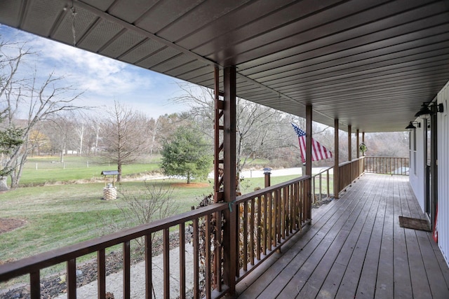 wooden terrace featuring a lawn and a porch