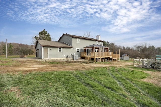 rear view of house featuring a deck, central air condition unit, a gazebo, a yard, and a shed