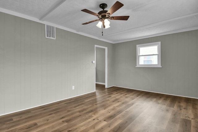 spare room featuring ceiling fan, dark hardwood / wood-style flooring, a textured ceiling, and wooden walls