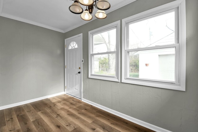 foyer featuring wood-type flooring, crown molding, and a chandelier